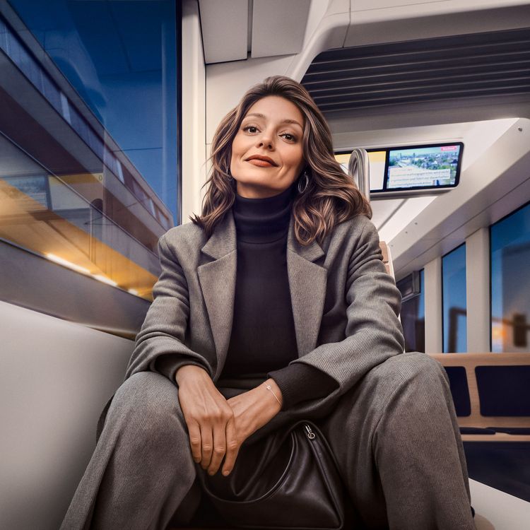 Business-Reise in der Tram Lächelnde Frau in elegantem grauem Business-Anzug und schwarzem Rollkragenpullover sitzt entspannt am Fenster eines modernen Zugabteils mit schwarzer Handtasche vor ihr stehen.